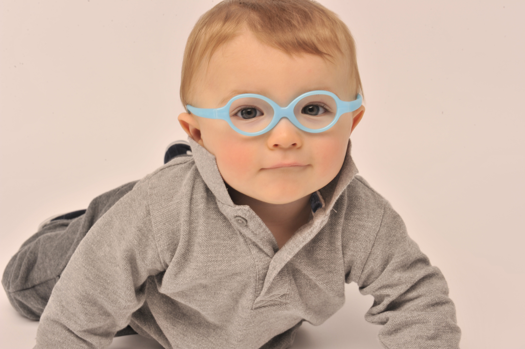 Infant boy wearing blue rubber eyeglasses frames