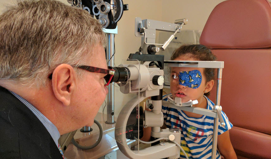 Doctor examining young girl in the phoropter