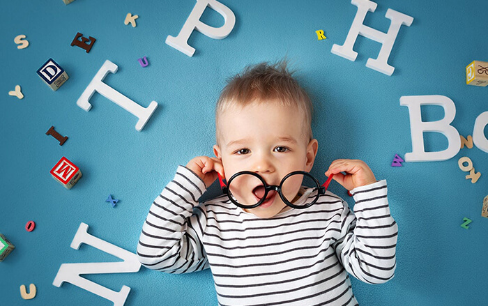 Toddler playing with a pair of black and red oversized frames laying on the floor