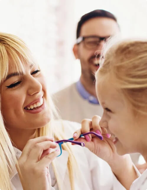 Optician trying on a pair of eyeglasses on a child both seem to be enjoying the experience